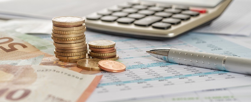 Euro notes and coins with calculator and biro as symbols for the calculation of fees for translation & localization services